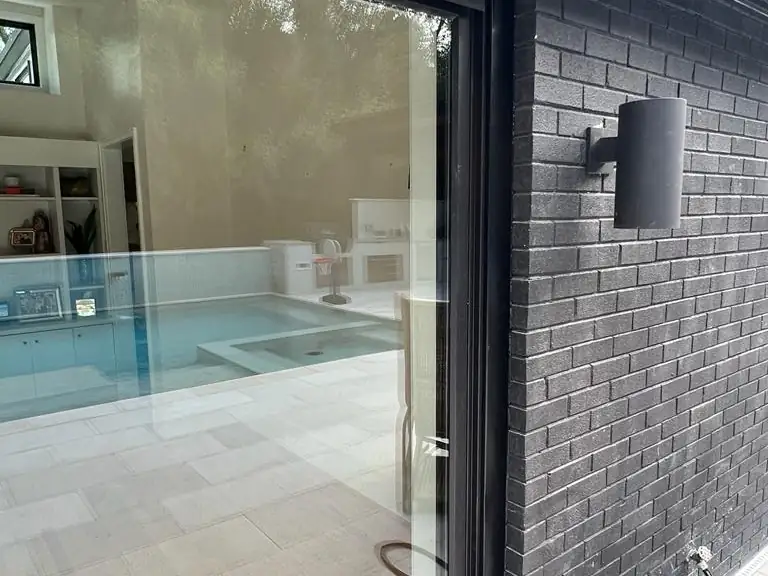 The finished four-panel glass door unit in the same wall, looking through to the pool